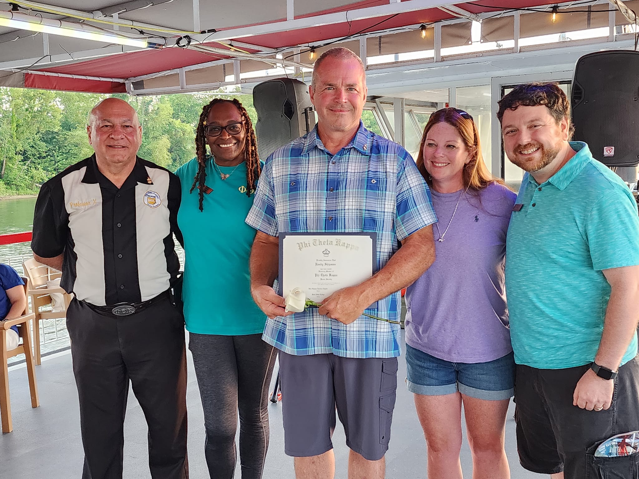 Randy Shipman holding a certificate, while surrounded by Phi Theta Kappans.