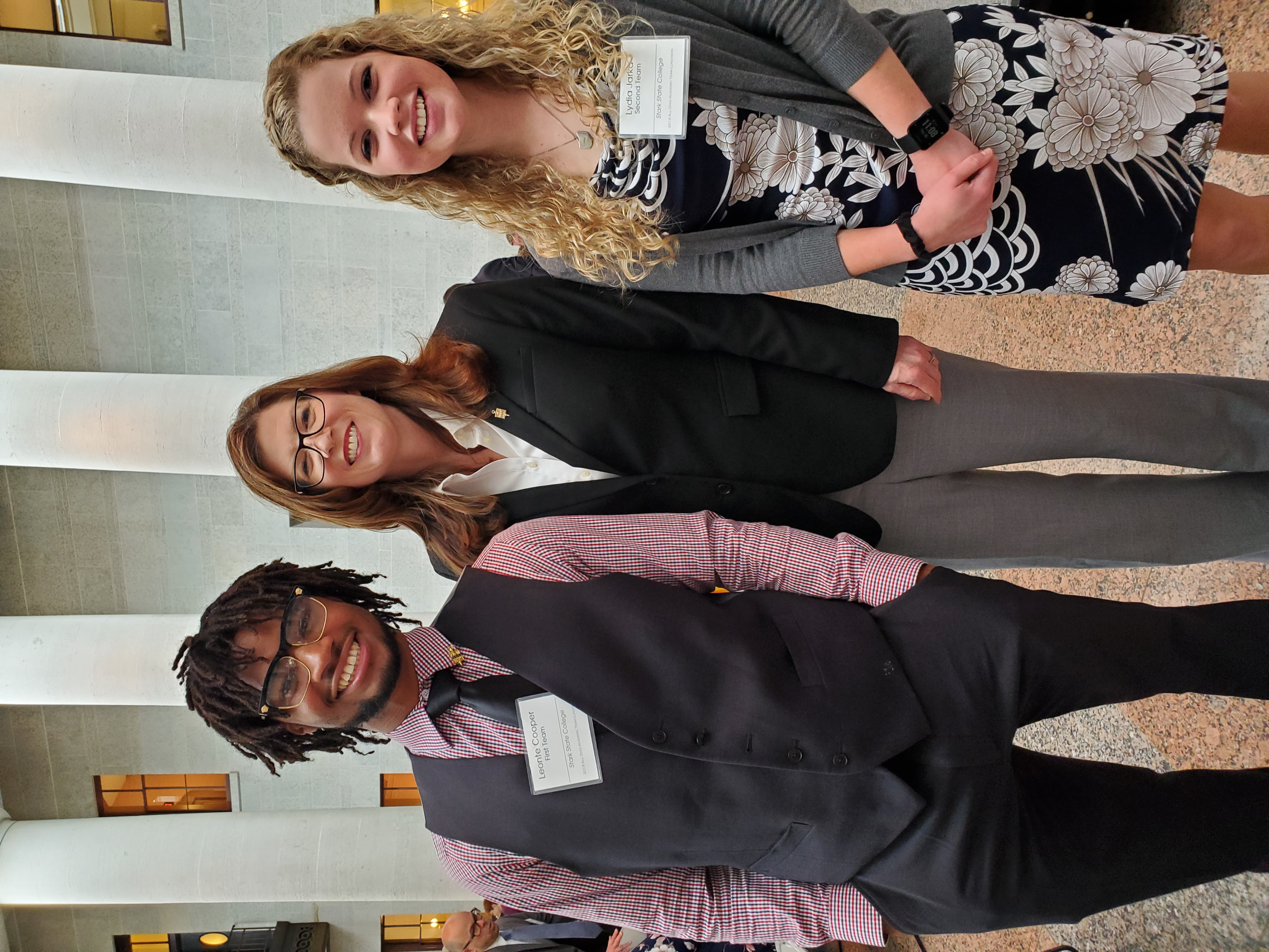 Three smiling Individuals dressed formally.